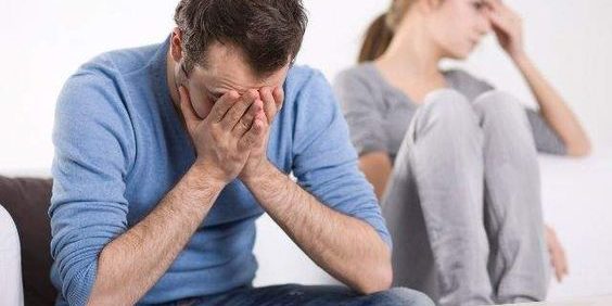 pareja en conflicto hombre y mujer sentados en un sofa tapandose la cara con una mano en gesto de angustia