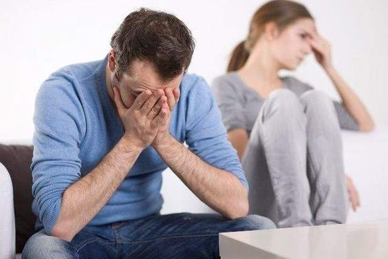 hombre y mujer sentados en un sofa tapandose la cara con una mano en gesto de angustia